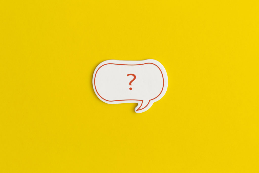 Paper speech bubble on a yellow background. Question mark